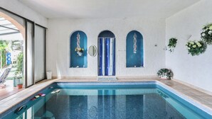 A swimming pool with a tiled edge, a door with a blue curtain, and a wall with decorative plants. - Homerez - Studio in Menton (Menton)