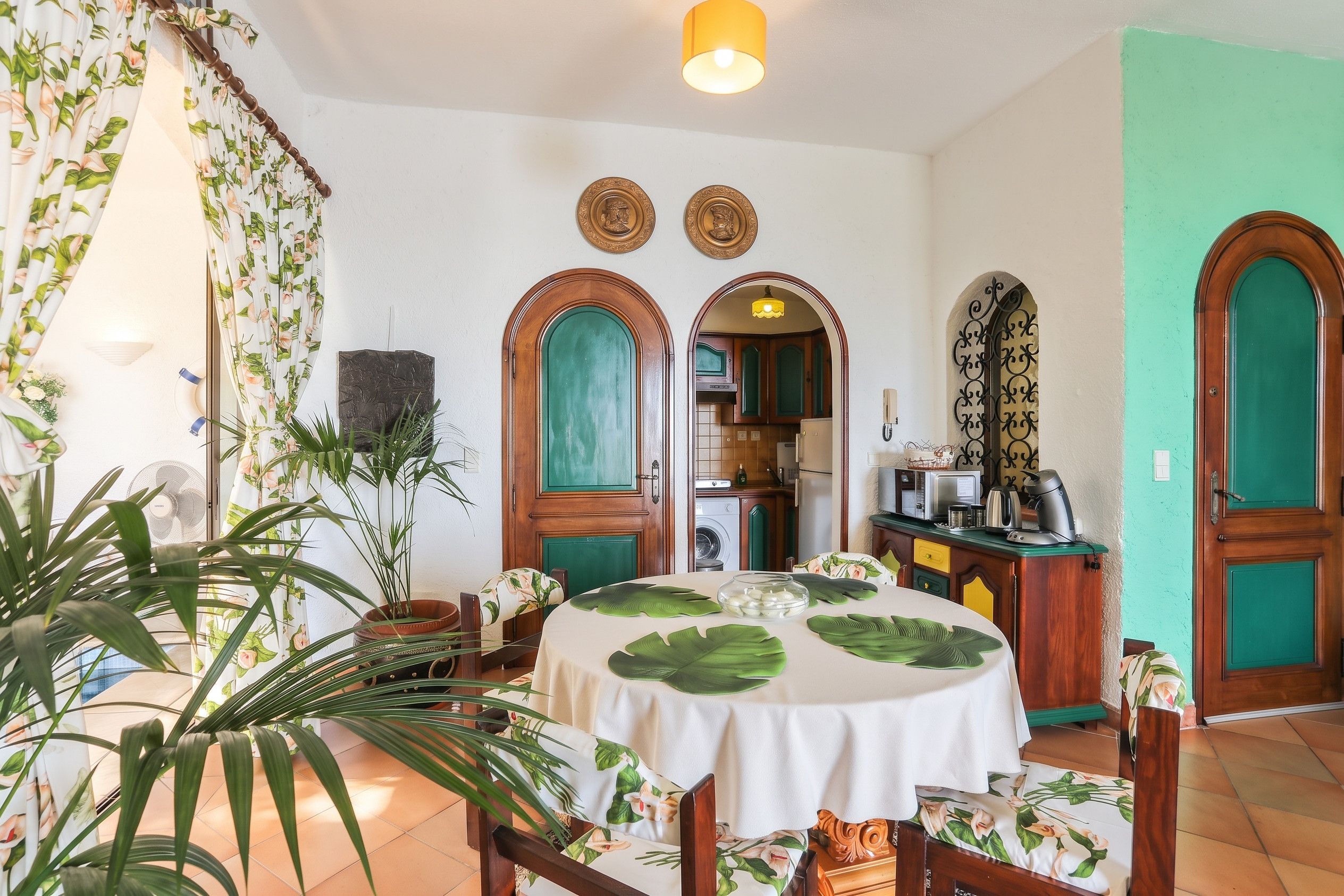 Ein Zimmer mit Esstisch, Stühlen, einer Küchenzeile und einer Treppe.