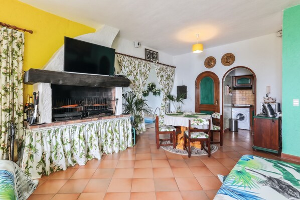 A living room with a fireplace, dining table, and kitchen area. - Homerez - Studio in Menton (Menton)