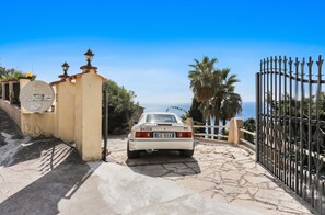 A white car parked at a gated entrance with a stone pathway leading to a coastal view. - Homerez - Studio in Menton (Menton)