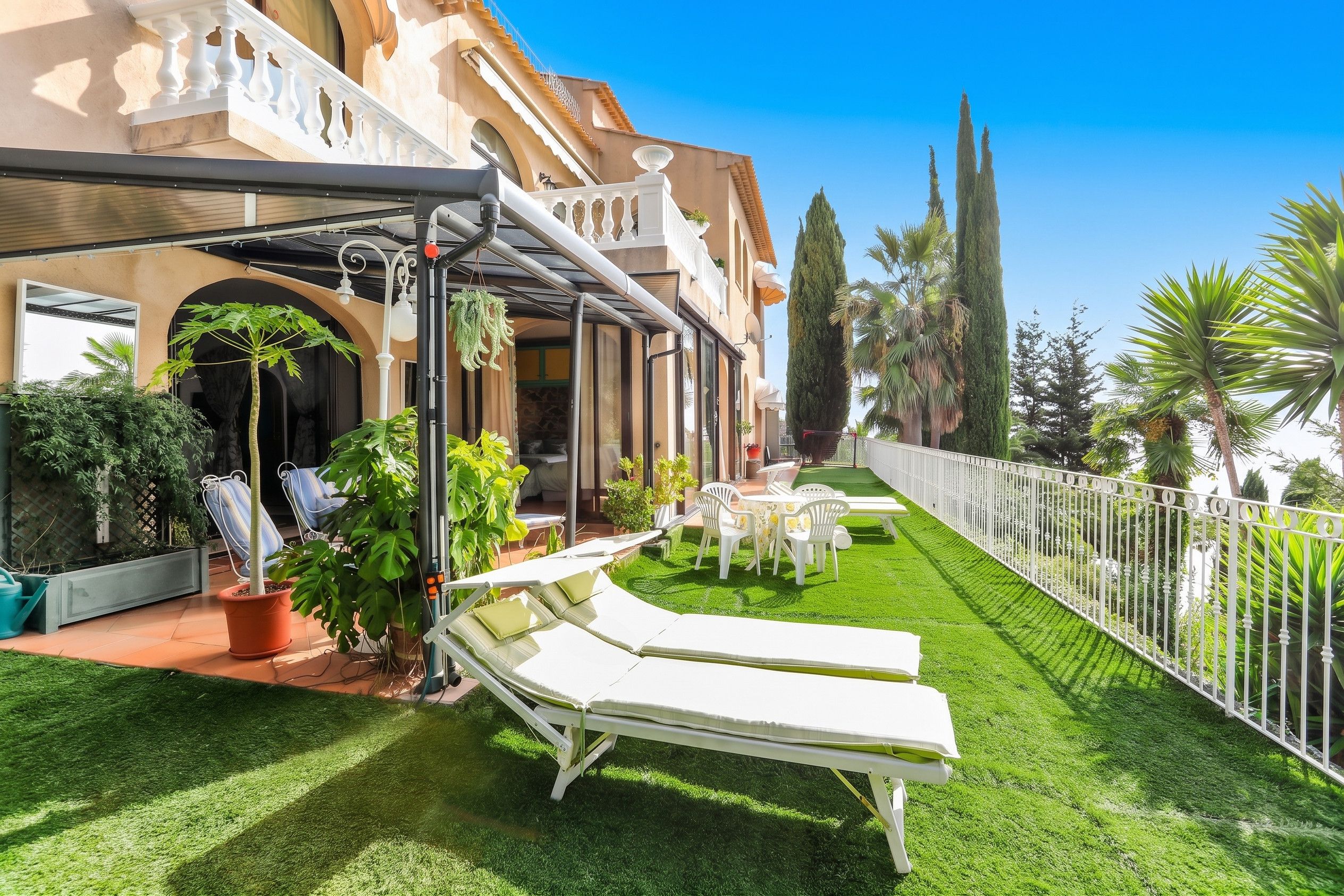 Ein Hotelinnenhof mit Pool, Liegestühlen und einem gepflegten Rasen.