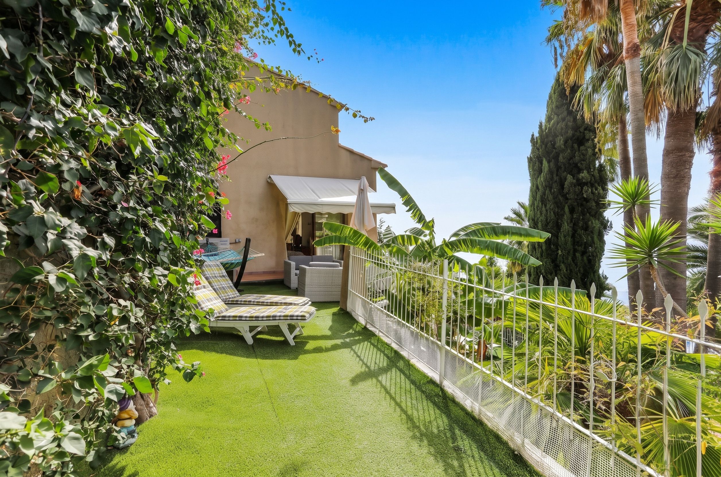 Ein privater Garten mit Pool, Liegestühlen und einem weißen Zaun.