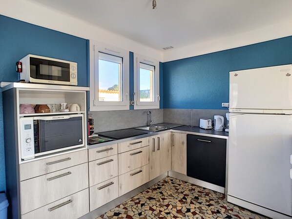 Compact kitchen with a modern design, light cabinetry, and a black countertop, featuring a microwave, toaster, and refrigerator.