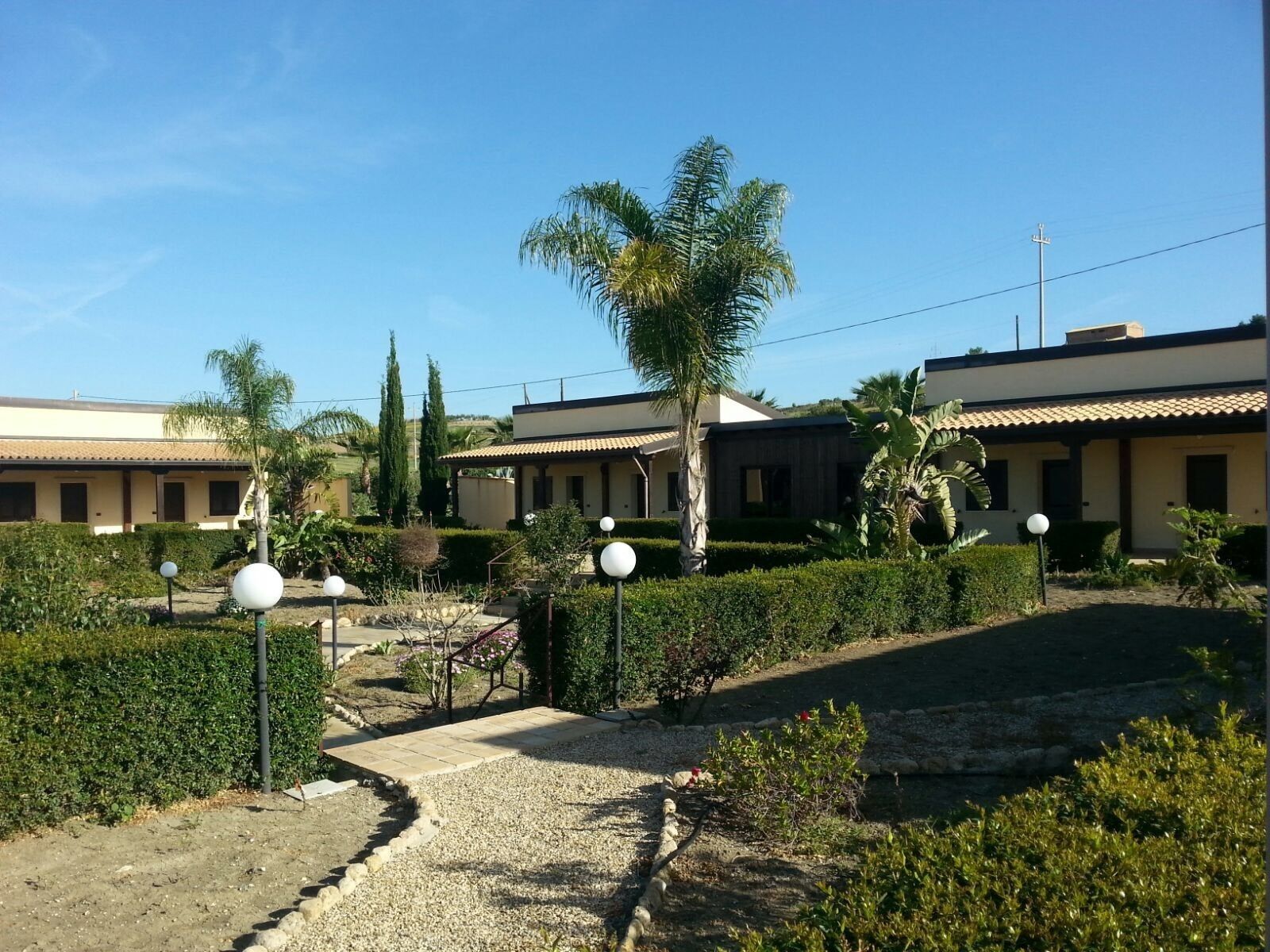 A residential area with multiple houses, a gravel pathway, and well-maintained gardens.