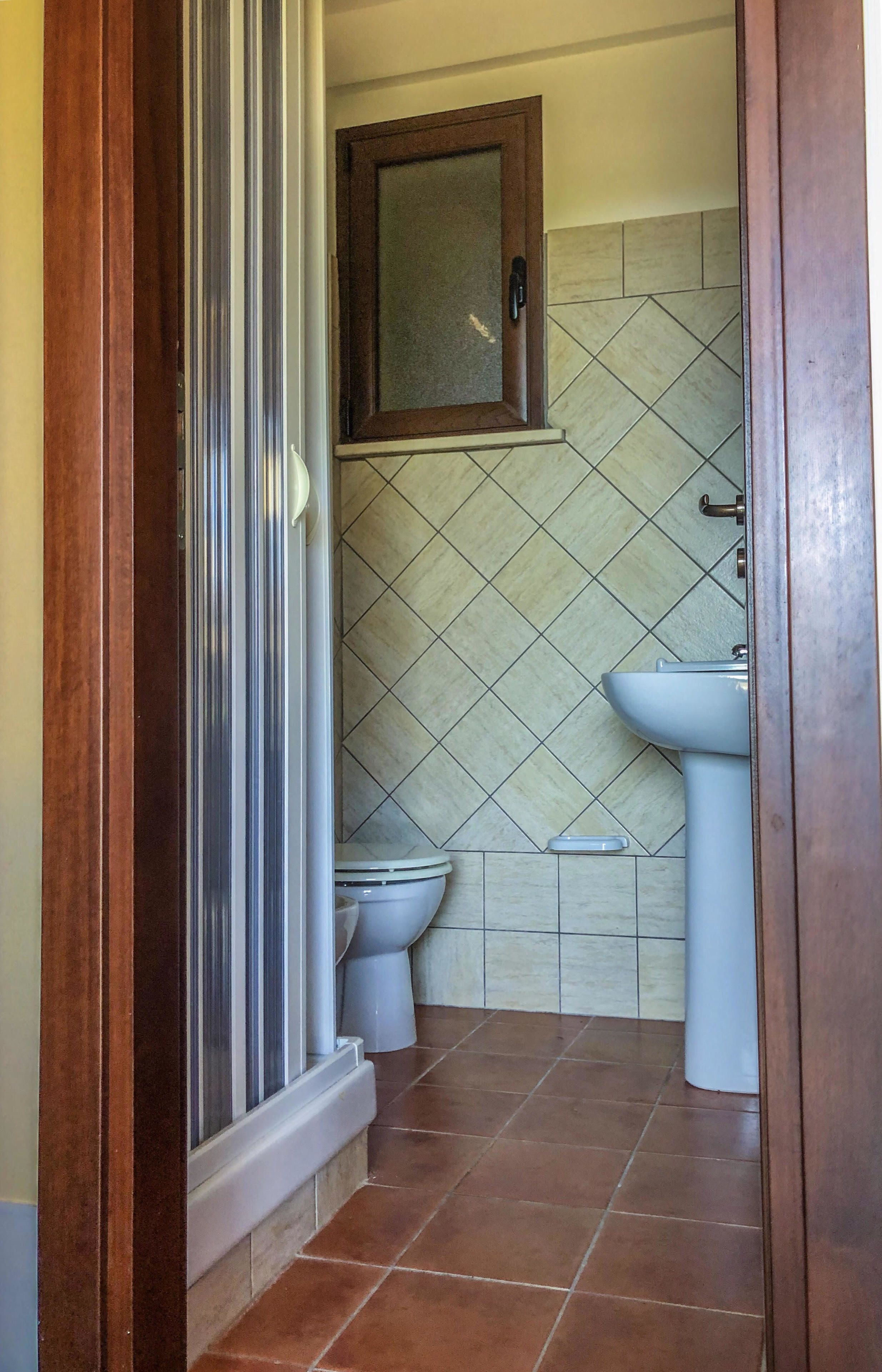 Un baño con inodoro, lavamanos y un armario sobre el lavabo.
