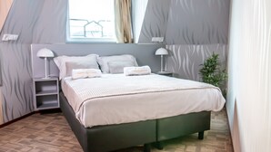 Een moderne slaapkamer met een groot bed, twee nachtkastjes en een raam met gordijnen.