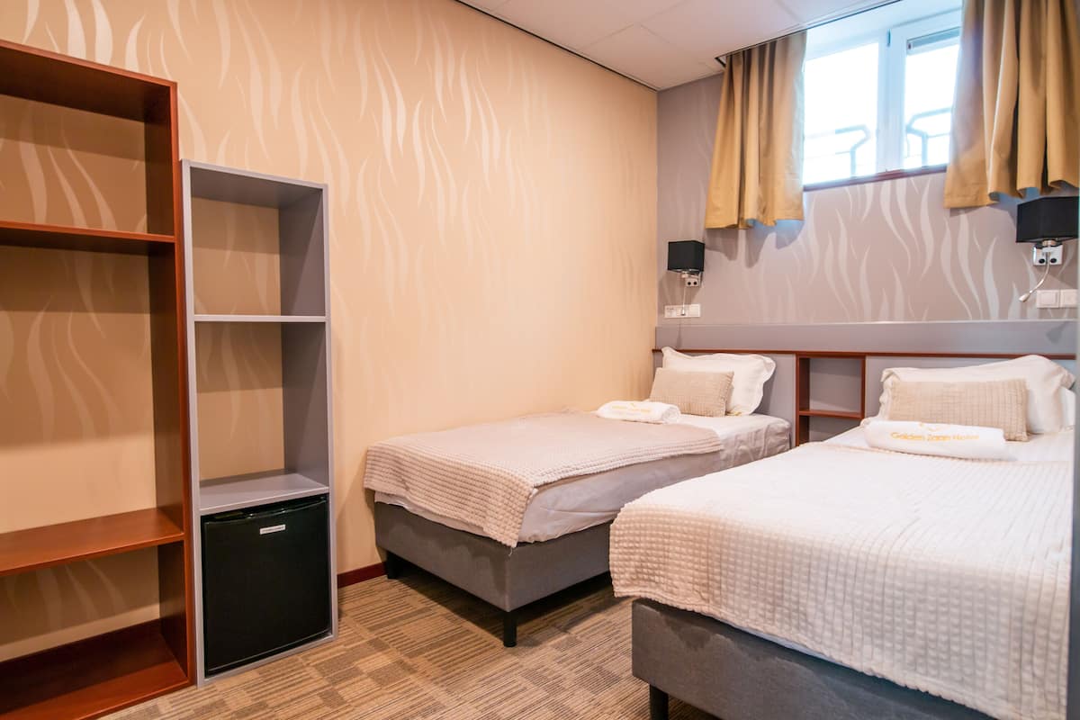 Una habitación de hotel con dos camas individuales, un escritorio pequeño y un armario.