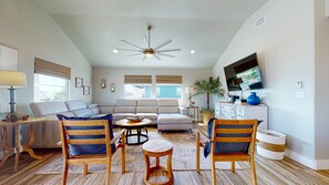 A spacious living room with a sectional sofa, wooden chairs, a coffee table, and a ceiling fan.