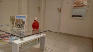 Ein Zimmer mit einem Glastisch, einem weißen Schrank und einer roten Vase.