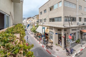 Vista de una calle con edificios, mesas al aire libre y una señal de prohibido el paso.
