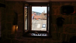 A stone-walled room with a window overlooking a town. - Apartments Zecic (Split)