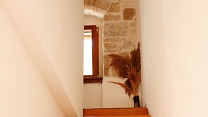 A wooden staircase leading to a room with a stone wall and a window. - Apartments Zecic (Split)