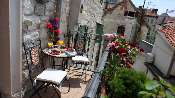 A small outdoor dining area with a table and chairs, a flower arrangement, and a view of the surrounding buildings. - Apartments Zecic (Split)