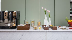 A coffee station with multiple espresso machines, a coffee cup, sugar packets, and a vase with flowers. - Maison Ottavia (Rome)