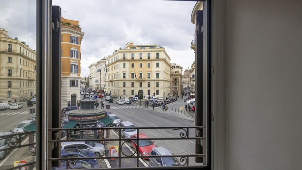 A view from a window overlooking a busy street with buildings and cars. - Maison Ottavia (Rome)