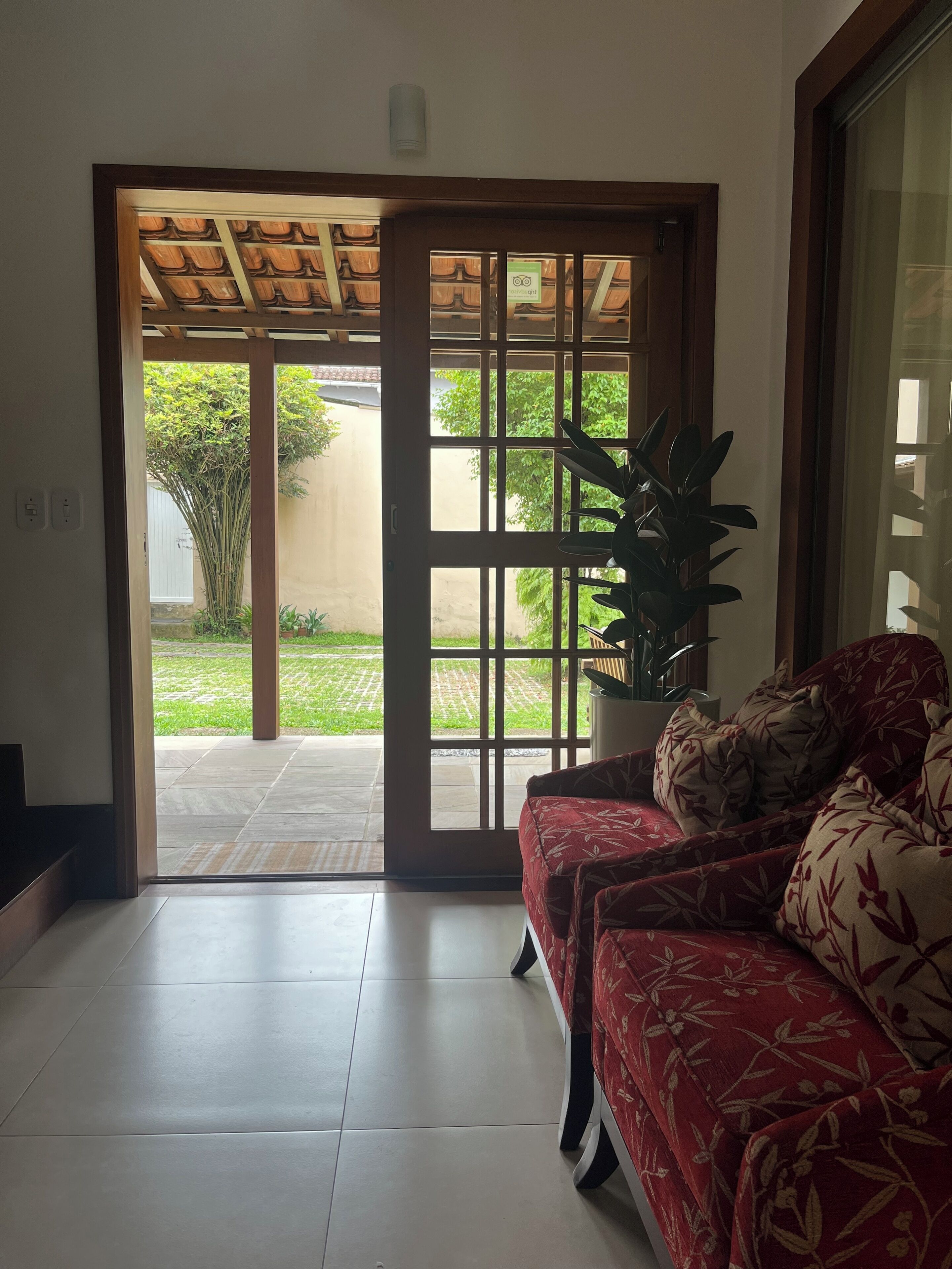 Una habitación con puerta corrediza de vidrio que da a un patio, un sofá con tapicería floral y una planta en maceta.