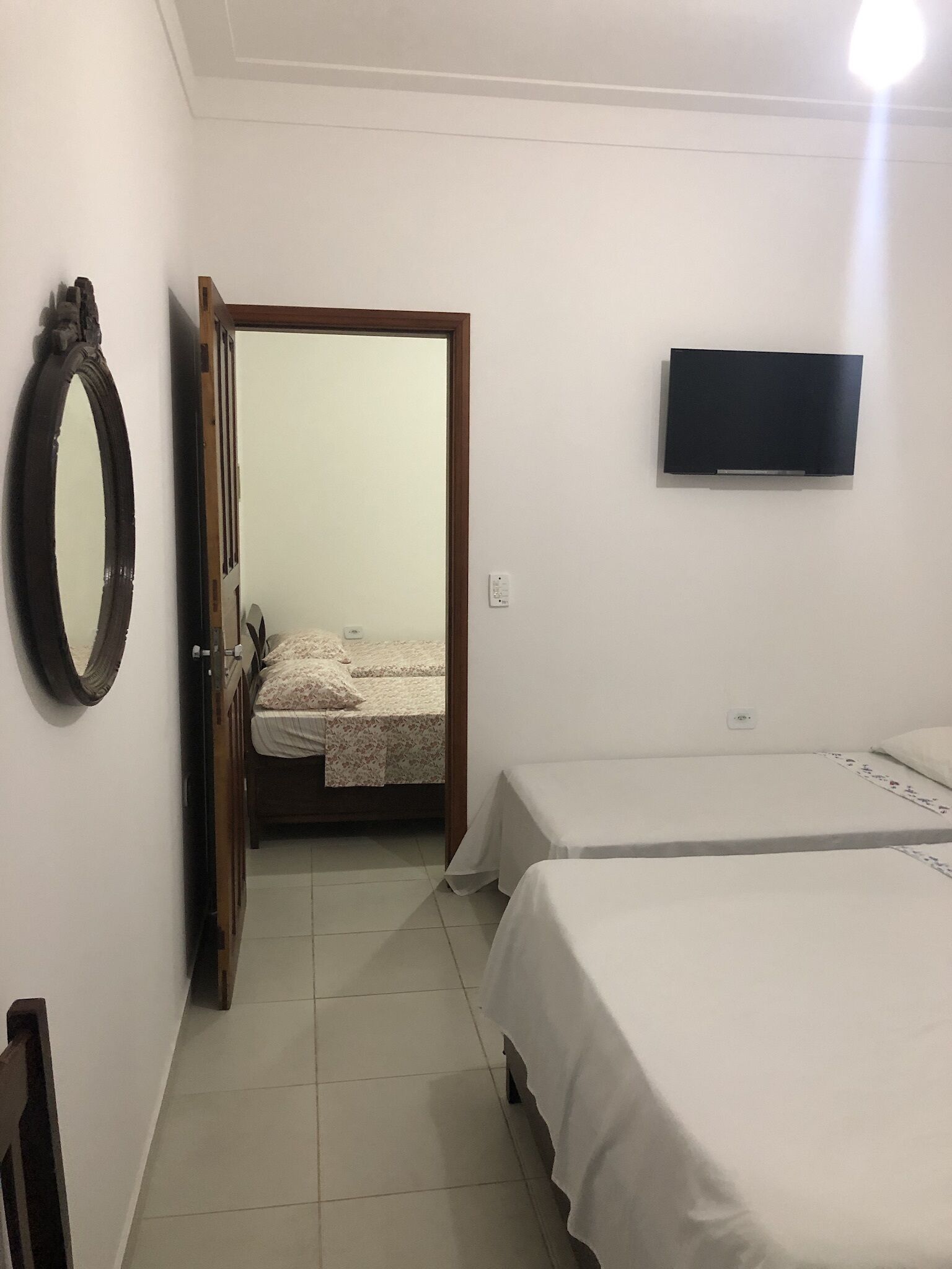 Un dormitorio con dos camas, un televisor montado en la pared y un espejo a la izquierda.