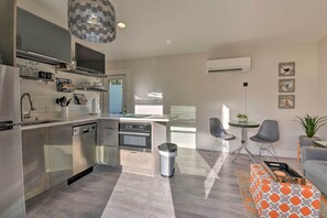 Uma cozinha moderna com eletrodomésticos de aço inoxidável, uma ilha central e um espaço de refeições com uma mesa redonda e cadeiras.