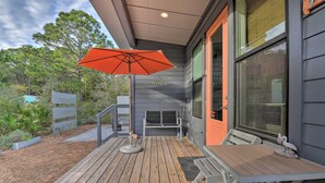 A wooden deck with a table and chairs, an umbrella, and a bench.