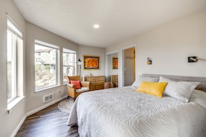 Quarto com uma cama grande, cômoda, cadeira e janela com vista para uma casa.