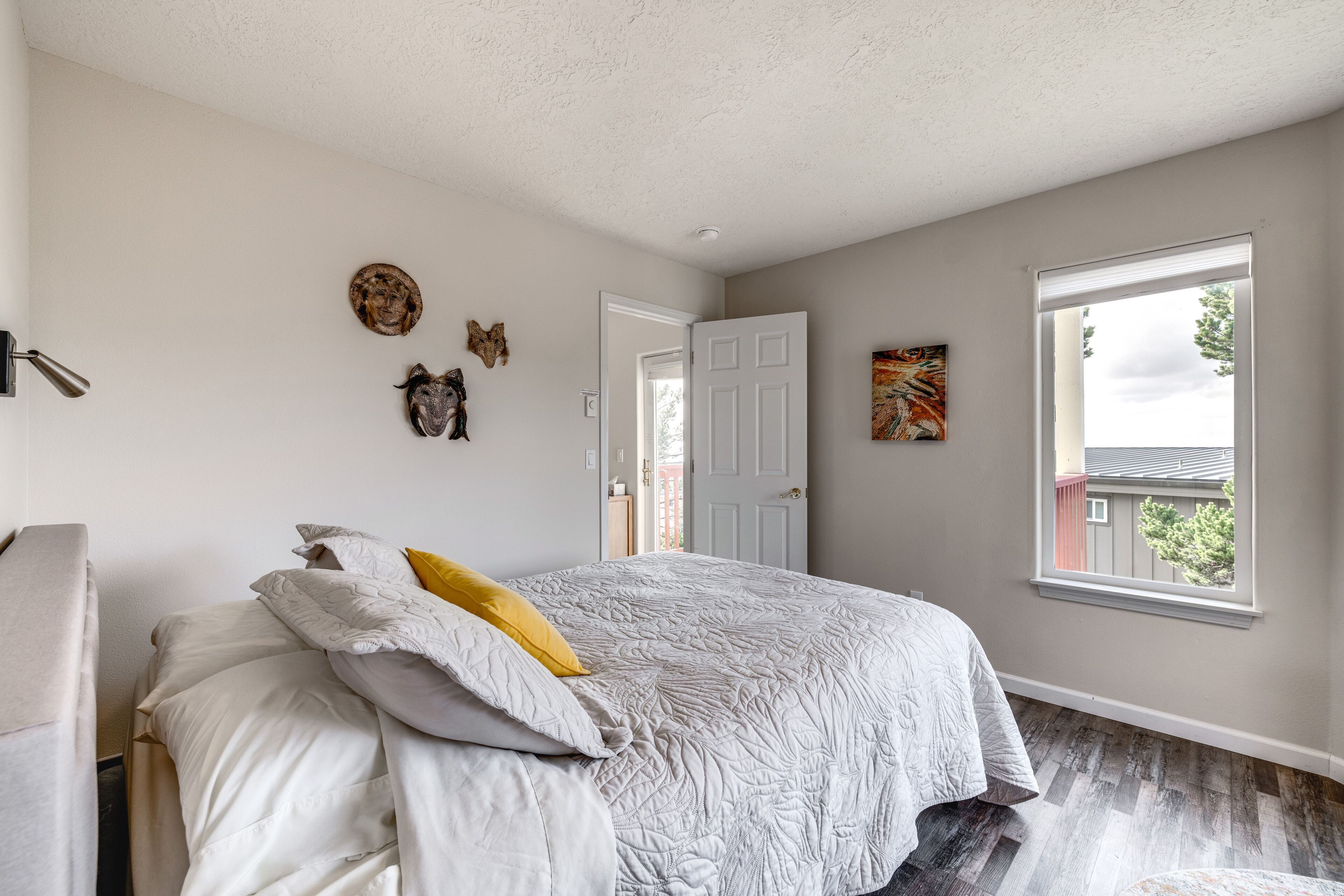 A bedroom with a bed, a door, a window, and wall decorations.
