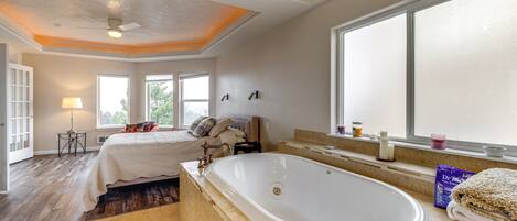 A spacious bedroom with a large bed, a walk-in closet, and a bathroom with a bathtub.