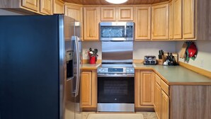 Una cocina con armarios de madera, un refrigerador de acero inoxidable, un microondas y un horno.