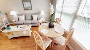 Una sala de estar acogedora con un sofá, una mesa de centro y una mesa de comedor lista para dos personas.