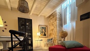 A cozy living room with a red sofa, a black chair, a globe, and a hanging light fixture. - Nonna Ninetta "typical Sicilian house" (Avola)