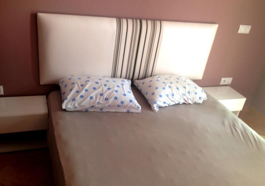 A bed with a striped headboard, two pillows with a polka dot pattern, and a plain mattress.