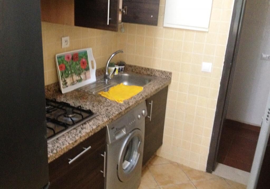 A compact kitchen with a gas stove, a sink, and a washing machine.