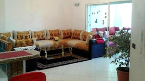 A living room with a sofa set, a coffee table, and a dining area with a table and chairs. - Beautiful apartment pool view in Marina Asilah 3923 (Asilah)