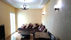 A living room with a sofa, a coffee table, a dining table, and a TV. - Residence Riviera Beach 4110 (Cabo Negro)