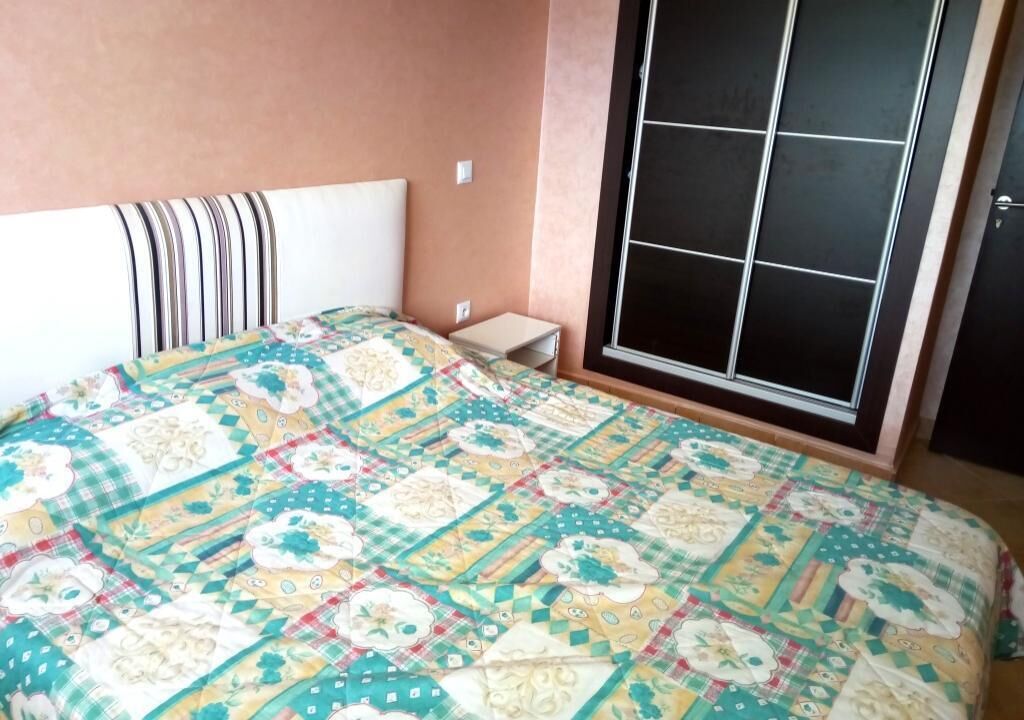 Une chambre à coucher avec un lit, une table de chevet et une fenêtre avec des stores.