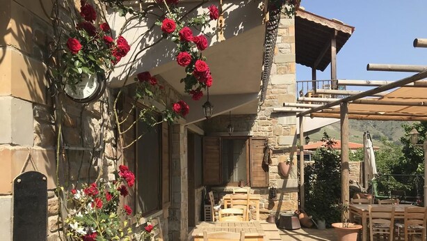 Un edificio de piedra con un patio amueblado con muebles de madera y plantas en macetas.
