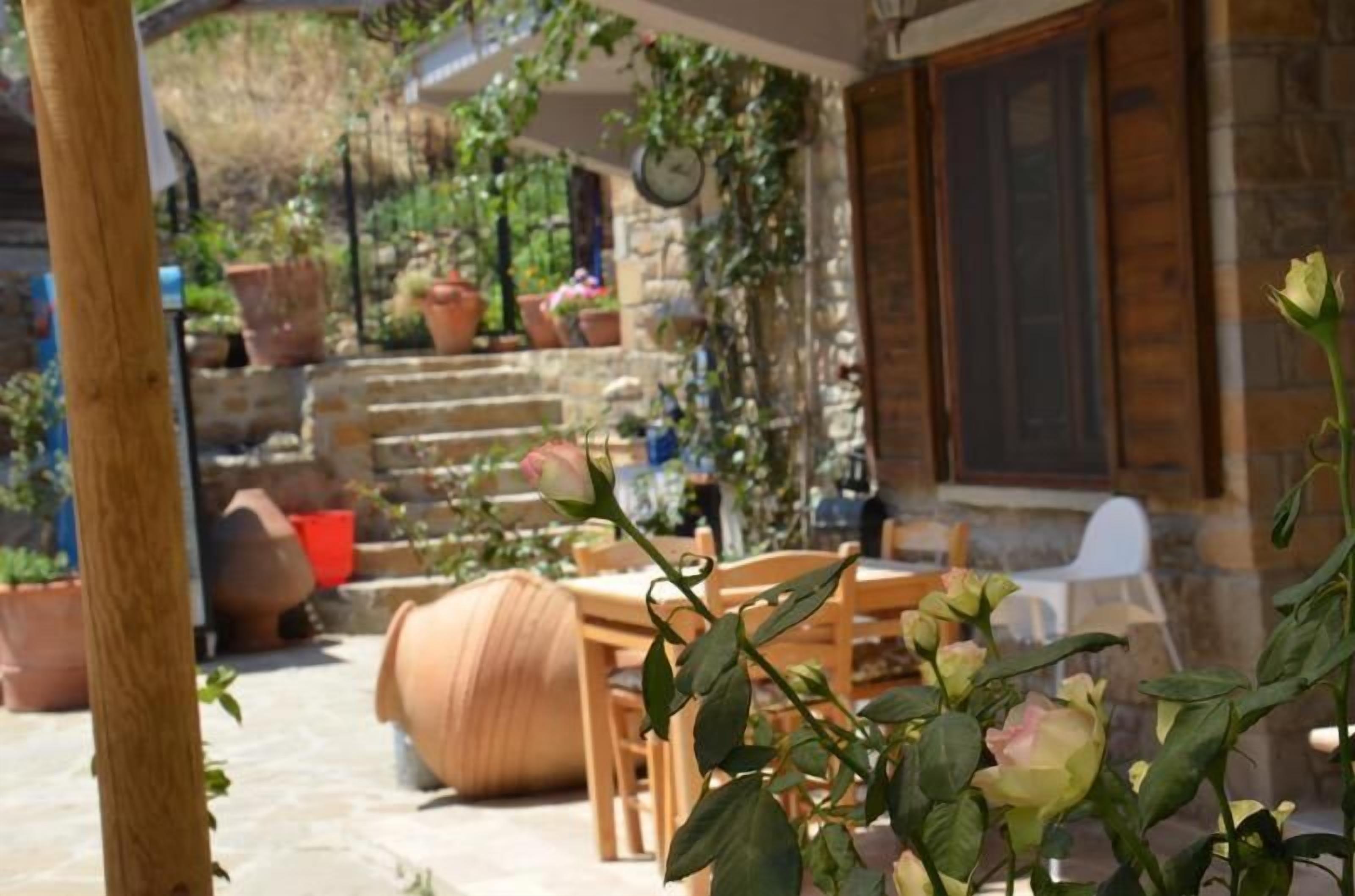 Un patio con una mesa de piedra, sillas y plantas en macetas.