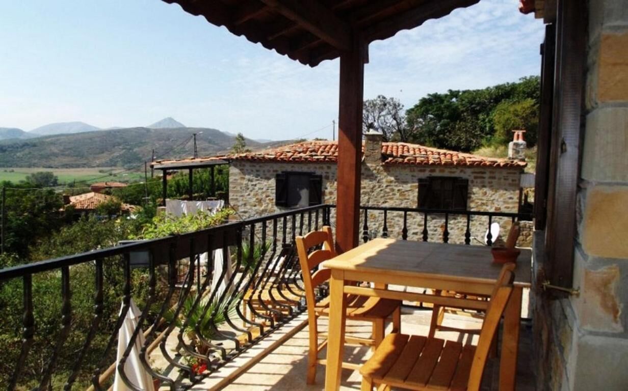 Un balcon avec une table et des chaises, donnant sur un paysage montagneux.
