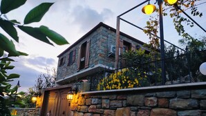 Un edificio de piedra con una puerta de madera, un balcón con flores amarillas y una pared de piedra.