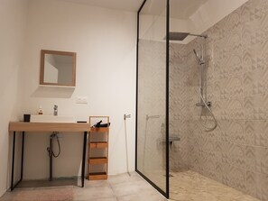 Ein modernes Badezimmer mit einer gläsernen Duschkabine, einem Holzlagerraum und einem Spiegel sowie einem fugenlosen Boden.
