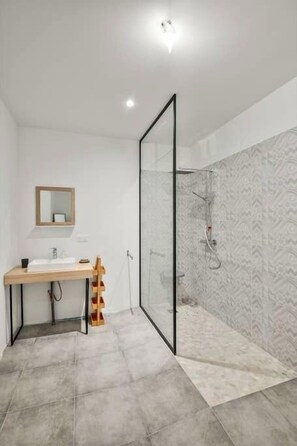 Ein modernes Badezimmer mit Duschkabine aus Glas, einem Holzbadezimmer-Möbel und einem Spiegel.