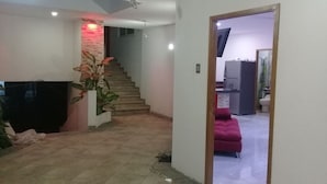 A modern living room with a staircase, a flat-screen TV, and a pink sofa. - PALMAS DE CHAHUE 1 (700 SF) (Bahías de HUATULCO)