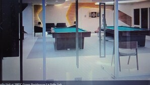 Ein Billardtisch in einem Raum mit Dartscheibe und einer Wanduhr.