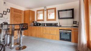 A modern kitchen with wooden cabinets, a stainless steel bar, and a built-in oven.