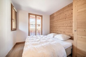 A bedroom with a wooden headboard, a large bed with white bedding, and a window with a view of a balcony. - Faronniere 5 : Duplex 3 bedrooms in village heart (MORZINE)