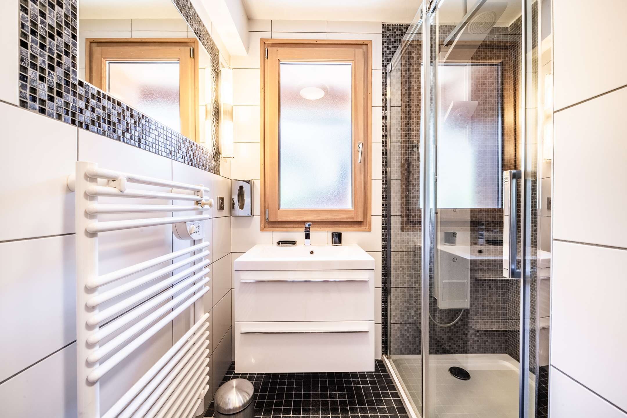 A modern bathroom with a white vanity, a glass shower enclosure, and a tiled backsplash.