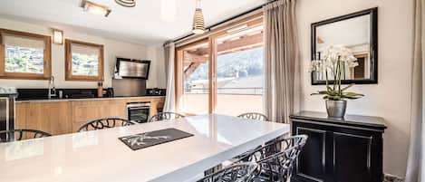 Une cuisine moderne dotée d’un grand îlot central, de meubles en bois et d’un coin repas avec des chaises en métal.