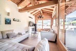 Sala de estar moderna com teto de madeira, sofá, mesa de centro e televisão.