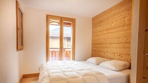 A bedroom with a wooden headboard, a bed with white bedding, and a sliding glass door leading to a balcony.