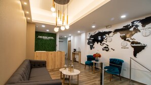 A hotel lobby with a reception desk, a sofa, two chairs, a small table with a vase, and a world map on the wall. - The Park Hotel (Guayaquil)