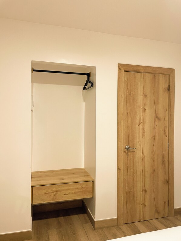 Una habitación con un armario de madera, un banco y una puerta.